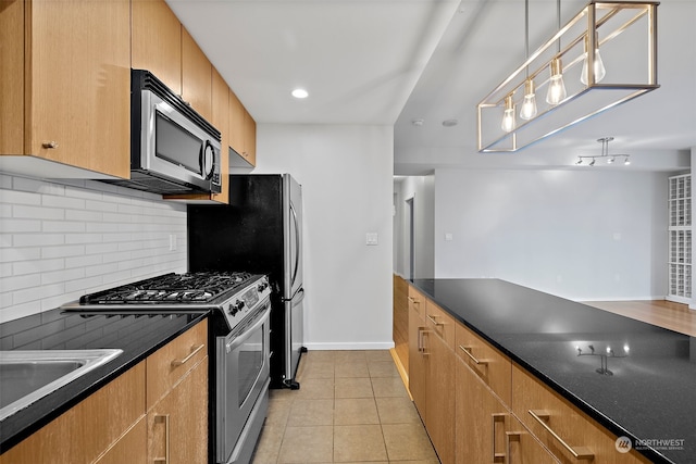 kitchen with appliances with stainless steel finishes, tasteful backsplash, decorative light fixtures, dark stone countertops, and light tile patterned flooring