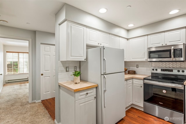 kitchen featuring appliances with stainless steel finishes, white cabinetry, baseboard heating, and light hardwood / wood-style floors