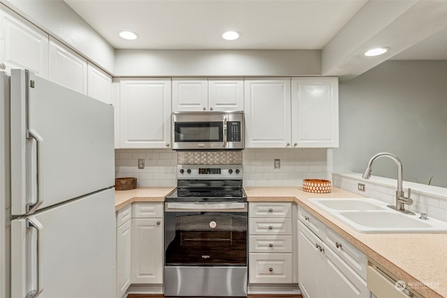 kitchen featuring stainless steel appliances, wood-type flooring, sink, white cabinets, and tasteful backsplash