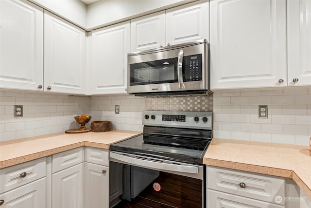 kitchen with appliances with stainless steel finishes, white cabinets, and tasteful backsplash