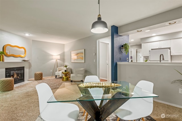 dining room featuring a fireplace and light colored carpet