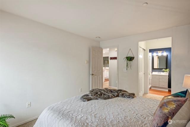 carpeted bedroom with ensuite bathroom and sink