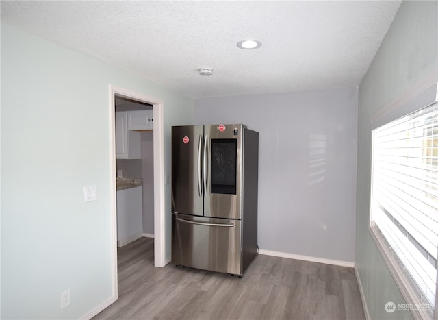 kitchen featuring stainless steel fridge, a textured ceiling, and light wood-type flooring