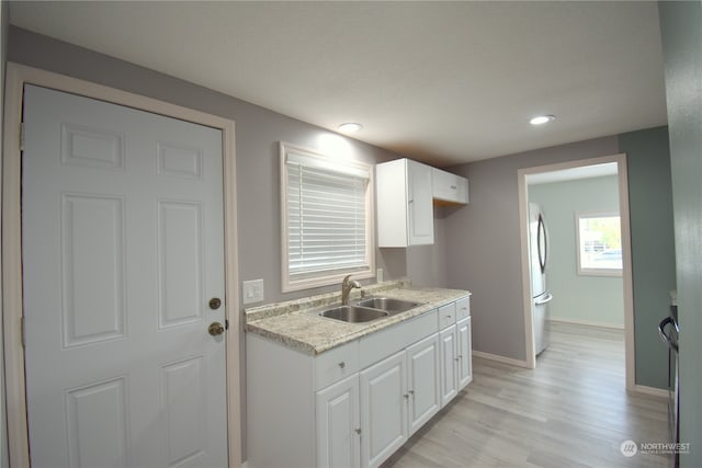 kitchen featuring stainless steel fridge, light stone countertops, sink, light wood-type flooring, and white cabinets