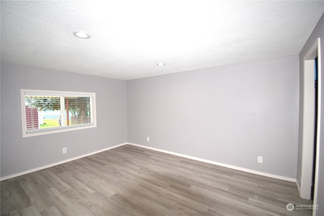 empty room with wood-type flooring and a textured ceiling