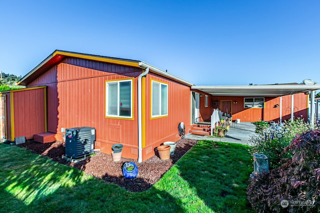 view of side of home with a yard and central AC unit