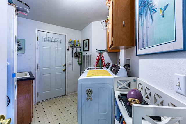 laundry area with cabinets, a textured ceiling, and separate washer and dryer