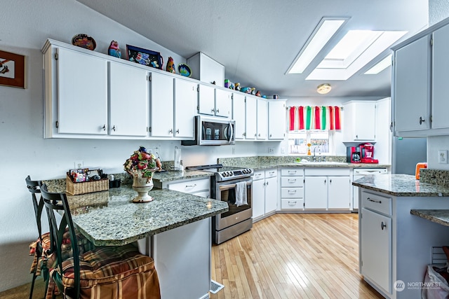 kitchen featuring appliances with stainless steel finishes, white cabinets, and dark stone countertops