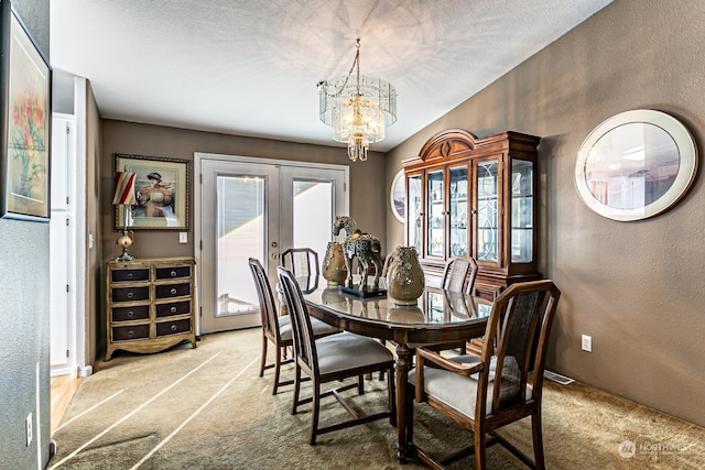 dining area featuring french doors, a textured ceiling, a notable chandelier, and carpet floors