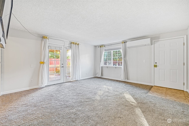 spare room featuring a wealth of natural light, an AC wall unit, a textured ceiling, and carpet flooring