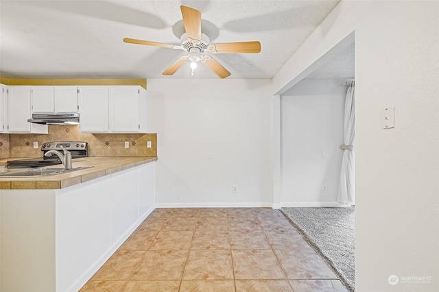 kitchen with sink, light tile patterned floors, white cabinets, a textured ceiling, and tasteful backsplash