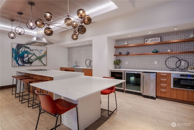 kitchen with a breakfast bar, decorative backsplash, decorative light fixtures, and stainless steel appliances