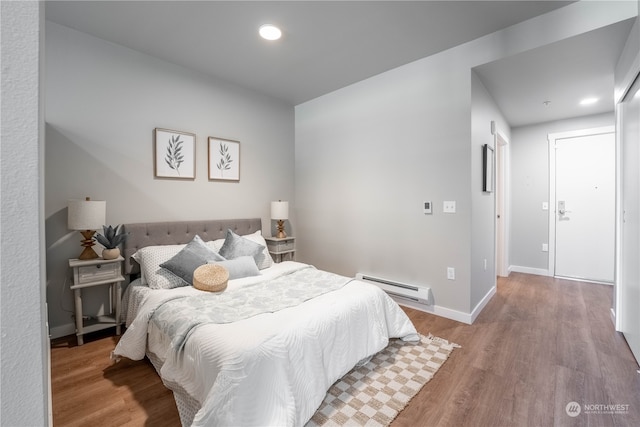 bedroom with baseboard heating and hardwood / wood-style floors