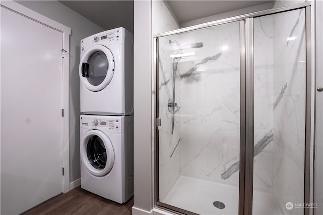 clothes washing area featuring stacked washer and dryer and dark hardwood / wood-style flooring