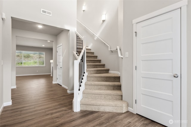 staircase with visible vents, baseboards, and wood finished floors