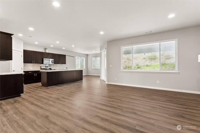 kitchen with stainless steel appliances, open floor plan, dark wood-style flooring, light countertops, and recessed lighting