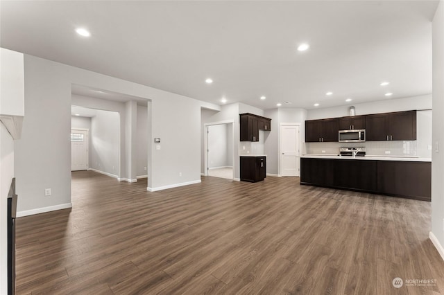 unfurnished living room with baseboards, dark wood finished floors, and recessed lighting