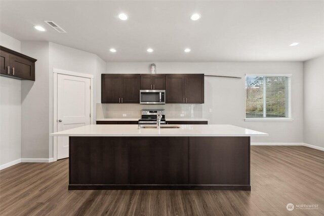 kitchen with a sink, visible vents, dark wood finished floors, light countertops, and appliances with stainless steel finishes