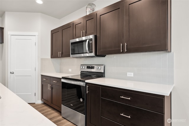 kitchen with light countertops, light wood-style flooring, dark brown cabinets, and appliances with stainless steel finishes