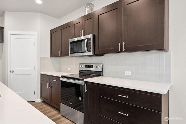 kitchen featuring light countertops, stainless steel appliances, light wood-type flooring, and dark brown cabinetry