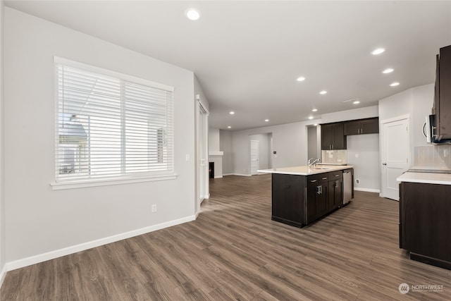 kitchen featuring decorative backsplash, light countertops, dark wood-type flooring, and a warm lit fireplace