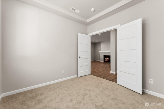 unfurnished bedroom with a large fireplace, carpet floors, baseboards, and visible vents