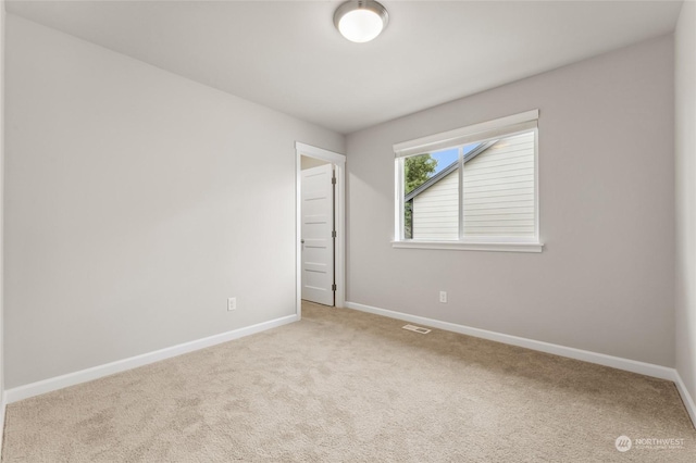 empty room with carpet flooring, baseboards, and visible vents