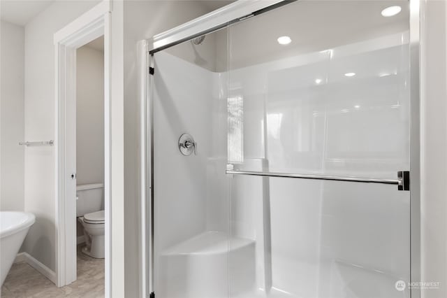 bathroom featuring recessed lighting, toilet, and a stall shower