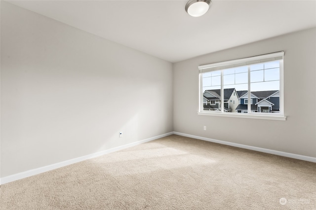 carpeted empty room featuring baseboards