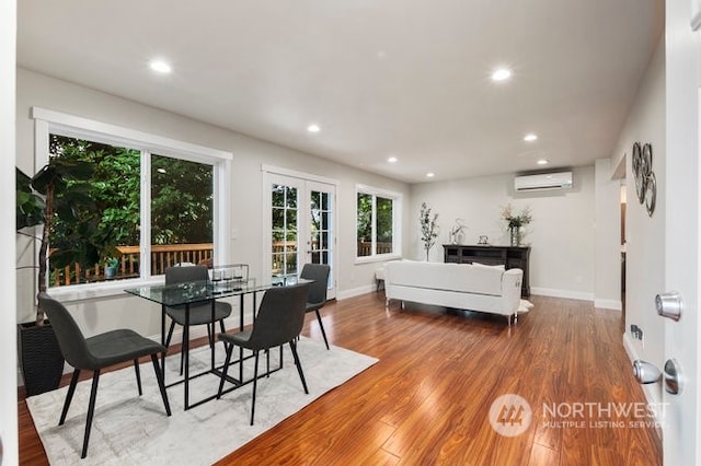 dining area featuring french doors, hardwood / wood-style floors, and an AC wall unit