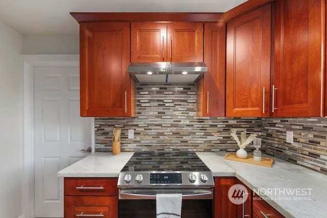 kitchen featuring light stone counters, stainless steel range oven, and backsplash