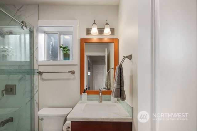 bathroom featuring vanity, toilet, and a shower with door