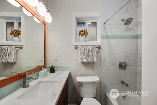 full bathroom with tiled shower / bath, vanity, and toilet