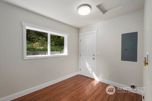 spare room with electric panel and dark hardwood / wood-style flooring