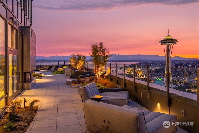 patio terrace at dusk featuring an outdoor living space, a balcony, and a mountain view