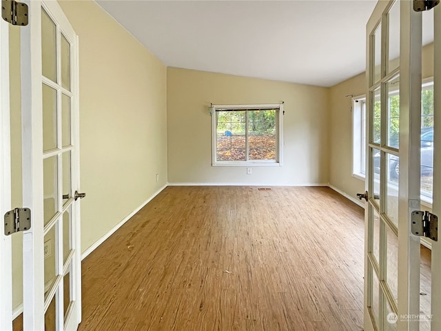 empty room with french doors, hardwood / wood-style flooring, and lofted ceiling