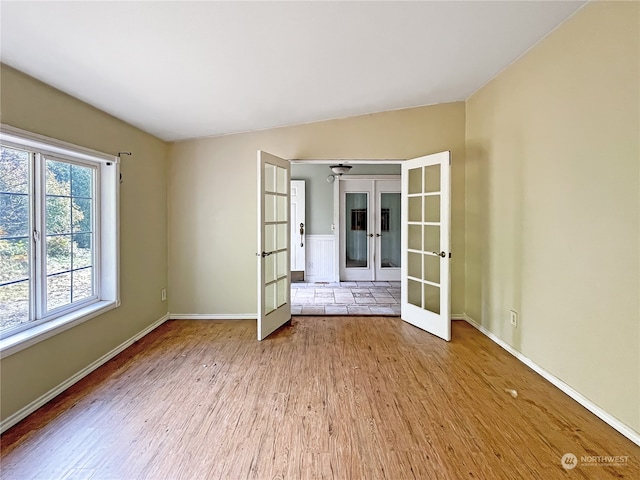 empty room featuring french doors, lofted ceiling, and light hardwood / wood-style flooring