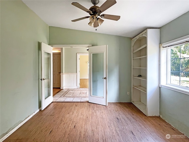 unfurnished bedroom featuring light hardwood / wood-style flooring, french doors, ceiling fan, and vaulted ceiling