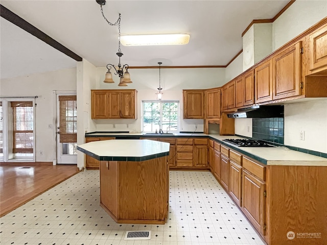 kitchen featuring gas stovetop, light hardwood / wood-style flooring, pendant lighting, crown molding, and a center island