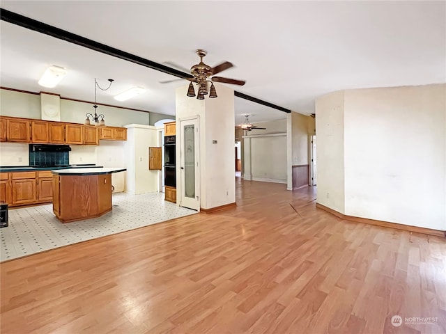 kitchen featuring a kitchen island, double oven, hanging light fixtures, light wood-type flooring, and ceiling fan