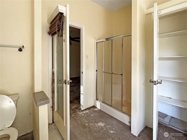 bathroom featuring toilet, concrete floors, and a shower with shower door