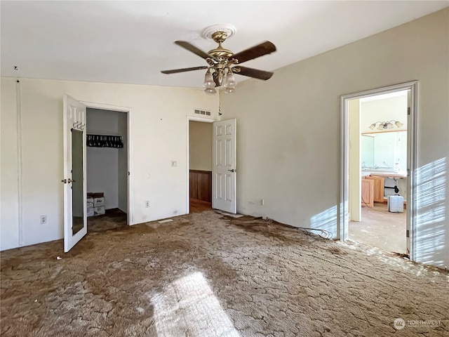 unfurnished bedroom featuring connected bathroom, a walk in closet, lofted ceiling, and ceiling fan