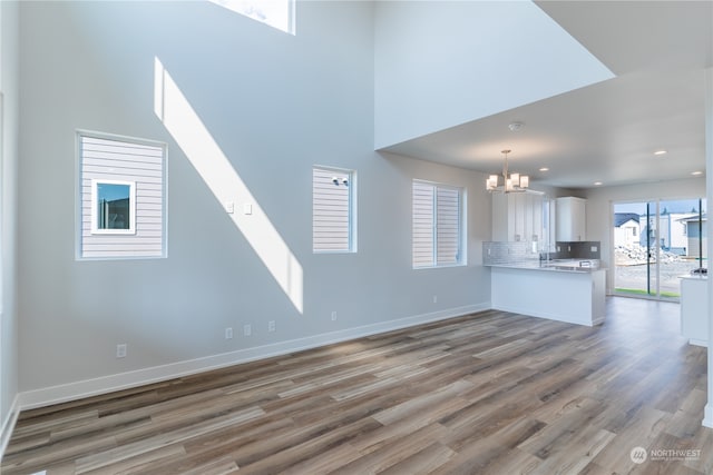 unfurnished living room with dark hardwood / wood-style flooring, a towering ceiling, a chandelier, and sink