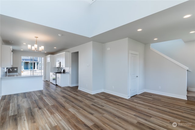 unfurnished living room featuring a chandelier, sink, and dark wood-type flooring