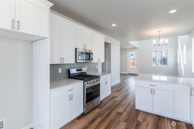 kitchen with appliances with stainless steel finishes, tasteful backsplash, a notable chandelier, white cabinets, and dark hardwood / wood-style floors