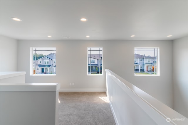 corridor with light colored carpet and a wealth of natural light