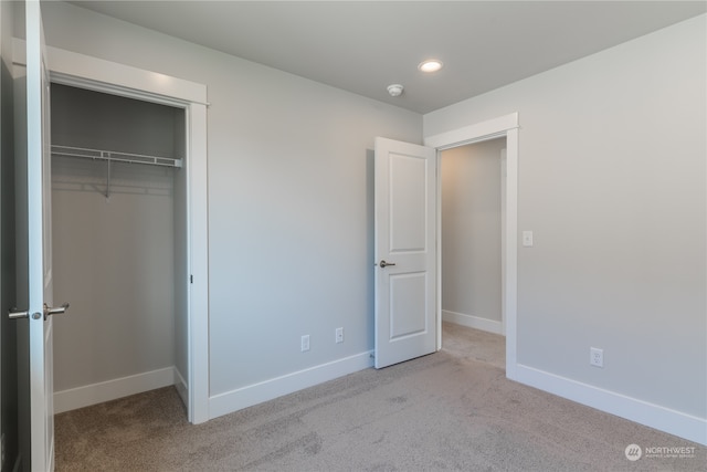 unfurnished bedroom with light carpet and a closet