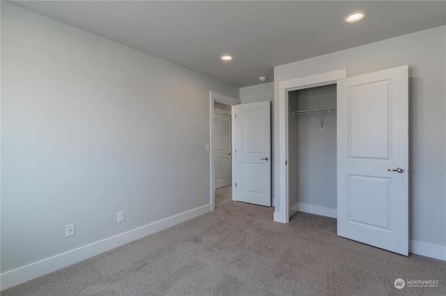 unfurnished bedroom featuring light carpet and a closet