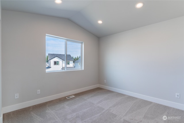 carpeted spare room featuring vaulted ceiling