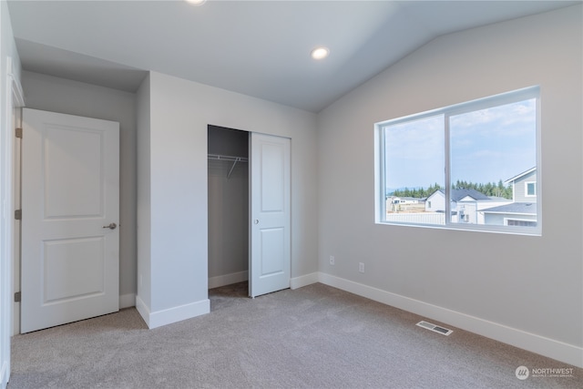 unfurnished bedroom featuring a closet, light colored carpet, and vaulted ceiling